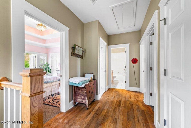 hallway with attic access, wood finished floors, and baseboards