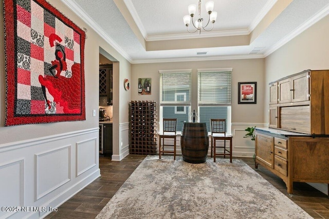 living area featuring crown molding, dark wood-style flooring, a chandelier, and a raised ceiling