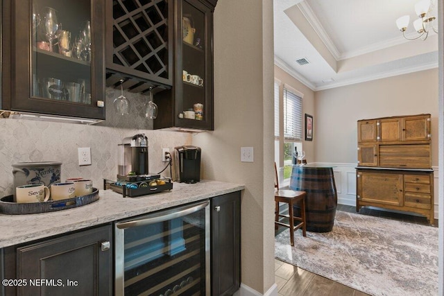 bar with crown molding, wine cooler, wood finished floors, tasteful backsplash, and a bar