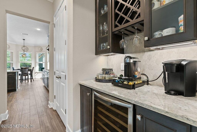 bar featuring a dry bar, beverage cooler, wood finished floors, backsplash, and ornamental molding