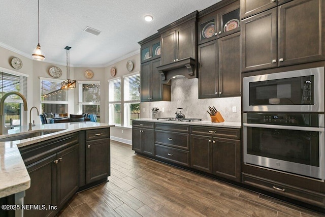 kitchen featuring visible vents, ornamental molding, appliances with stainless steel finishes, and dark brown cabinets