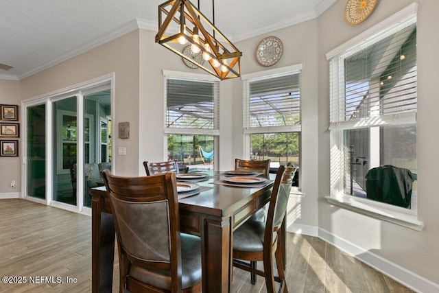 dining area with baseboards, crown molding, and wood finished floors