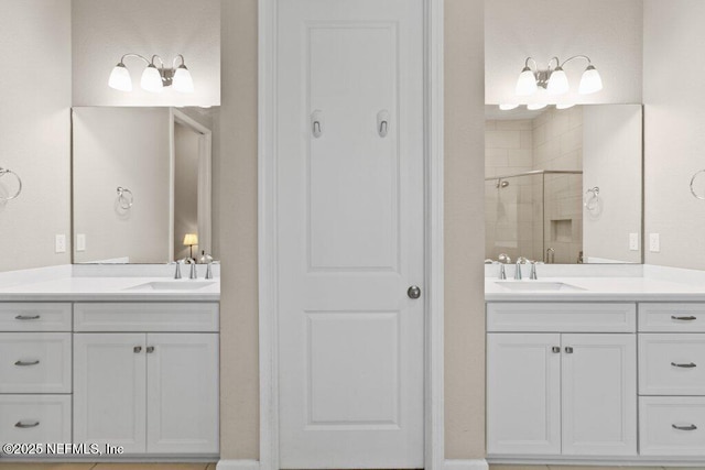 full bath featuring a sink, a stall shower, and two vanities