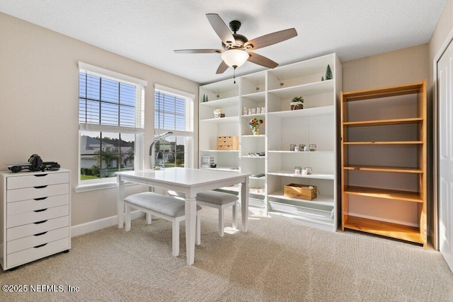 carpeted office with baseboards and a ceiling fan