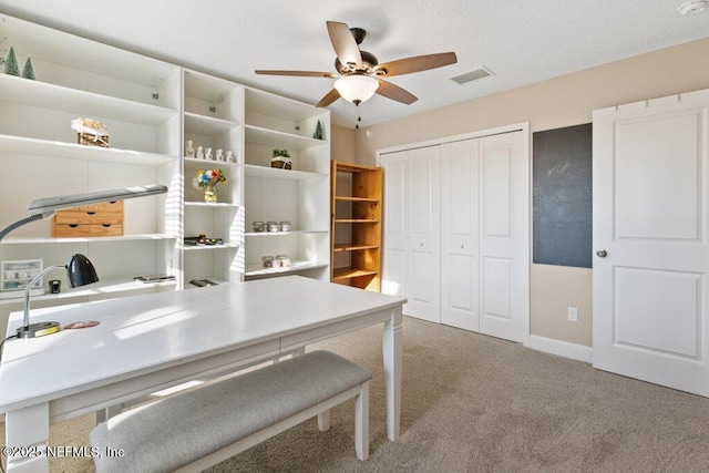 carpeted office space with ceiling fan, visible vents, and baseboards