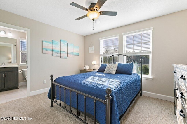 bedroom with light colored carpet, baseboards, ensuite bathroom, and multiple windows