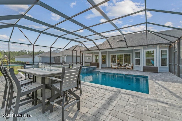 view of pool featuring outdoor dry bar, a ceiling fan, a patio area, glass enclosure, and a pool with connected hot tub