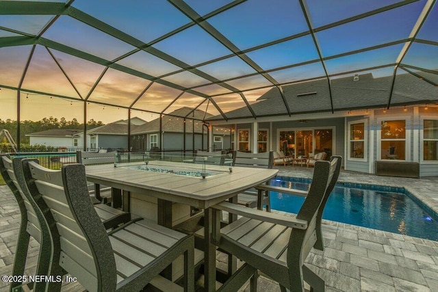 pool at dusk with a patio, an outdoor pool, a lanai, and outdoor dry bar