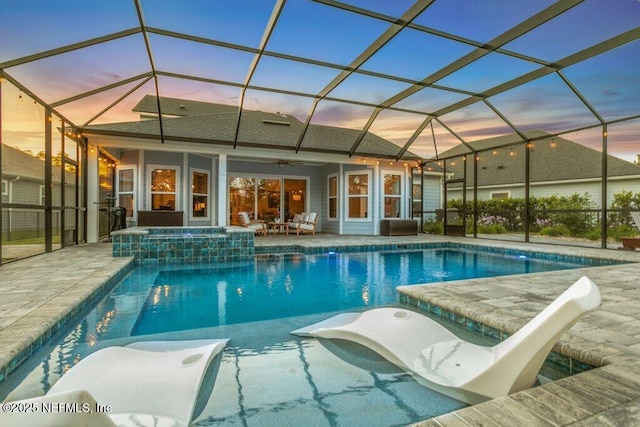 view of pool featuring glass enclosure, ceiling fan, a pool with connected hot tub, and a patio area