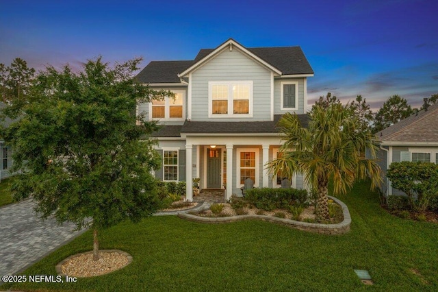 view of front of house featuring a shingled roof and a front lawn