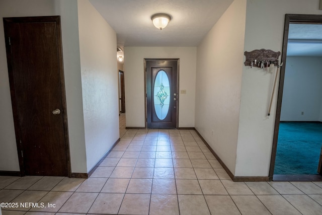 entryway with light tile patterned flooring and baseboards