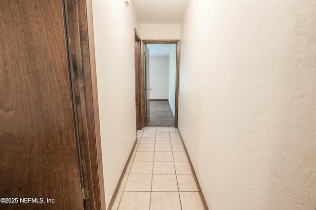 hall featuring light tile patterned floors and baseboards
