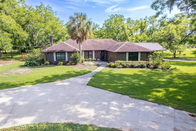 ranch-style home featuring a front lawn, a chimney, and brick siding