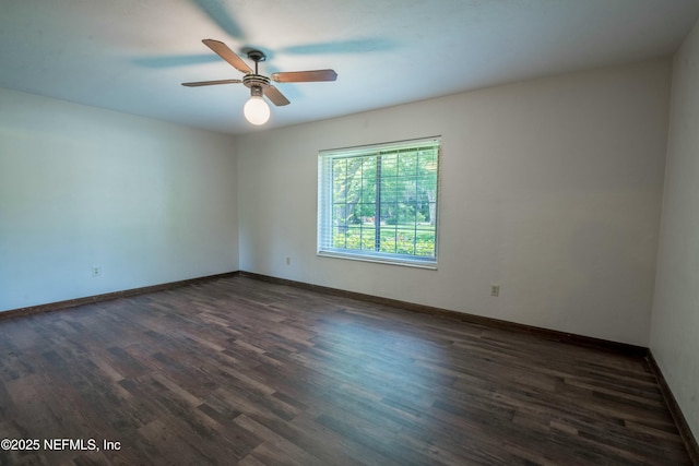 empty room with ceiling fan, dark wood finished floors, and baseboards
