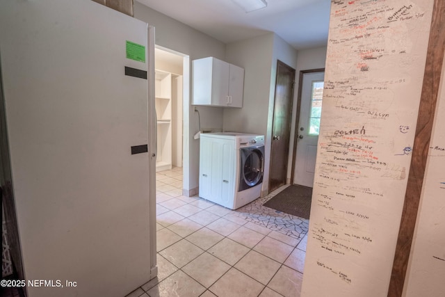 clothes washing area featuring light tile patterned floors, washer / dryer, and cabinet space