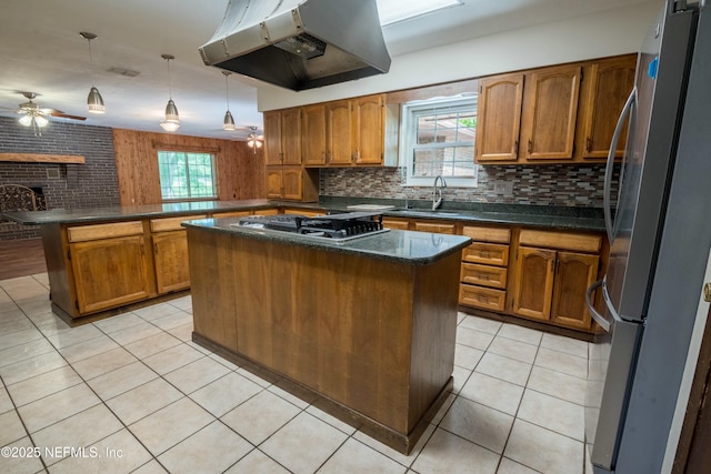 kitchen with brown cabinets, a sink, appliances with stainless steel finishes, under cabinet range hood, and a peninsula
