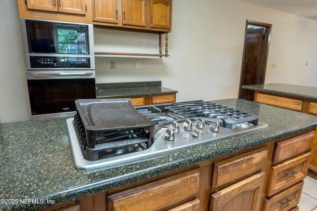 kitchen featuring tile patterned floors, brown cabinetry, open shelves, and appliances with stainless steel finishes