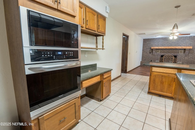 kitchen with light tile patterned floors, a brick fireplace, a ceiling fan, black microwave, and dark countertops