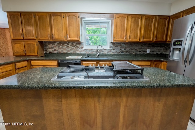 kitchen with brown cabinets, a sink, decorative backsplash, a center island, and appliances with stainless steel finishes