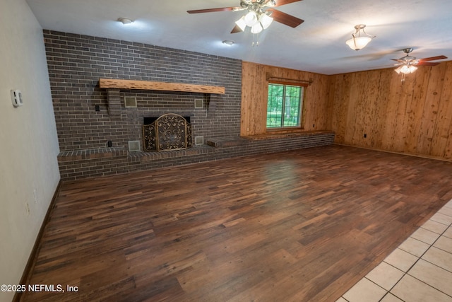 unfurnished living room with a fireplace, wood finished floors, ceiling fan, and baseboards