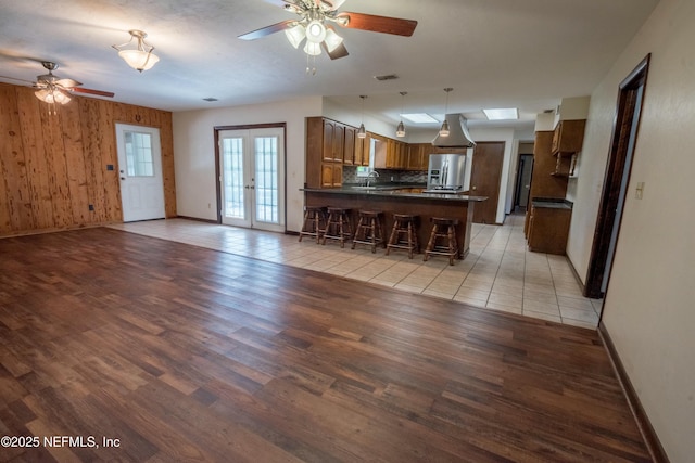 kitchen with dark countertops, a ceiling fan, a peninsula, and stainless steel fridge with ice dispenser