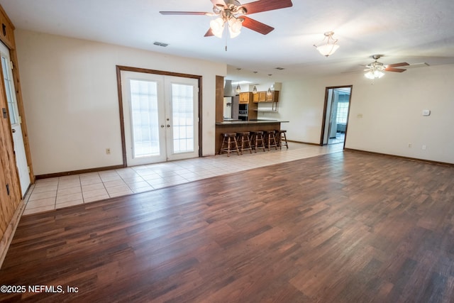 unfurnished living room featuring light wood-style flooring, ceiling fan, visible vents, baseboards, and french doors