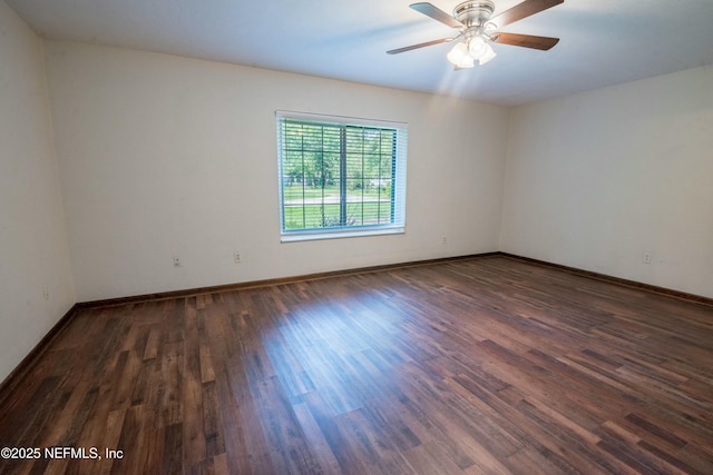 empty room with dark wood-style floors, baseboards, and ceiling fan