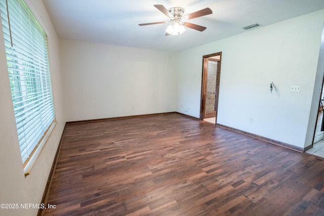 spare room featuring wood finished floors, visible vents, ceiling fan, and baseboards