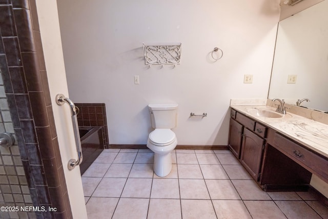 bathroom featuring baseboards, toilet, a bath, vanity, and tile patterned flooring