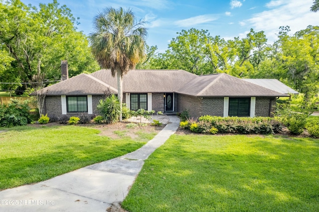 ranch-style home with a chimney, brick siding, and a front lawn