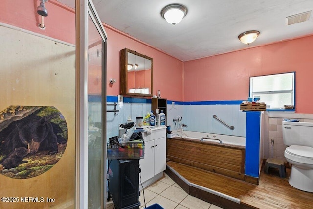 670 Hillsborough Ave, Florahome, FL 32140 - full bath with a shower stall, a wainscoted wall, toilet, a bath, and visible vents