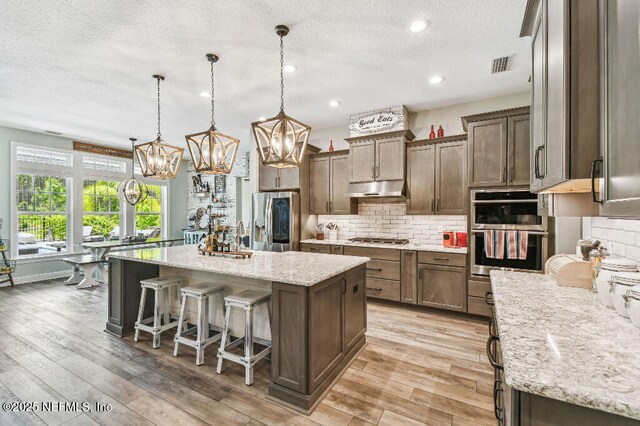225 Shinnecock Dr, Saint Johns, FL 32259 - kitchen featuring under cabinet range hood, visible vents, a textured ceiling, appliances with stainless steel finishes, and a notable chandelier