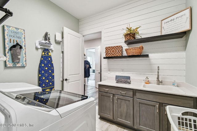 225 Shinnecock Dr, Saint Johns, FL 32259 - laundry room featuring washing machine and clothes dryer, light wood finished floors, a sink, wood walls, and cabinet space