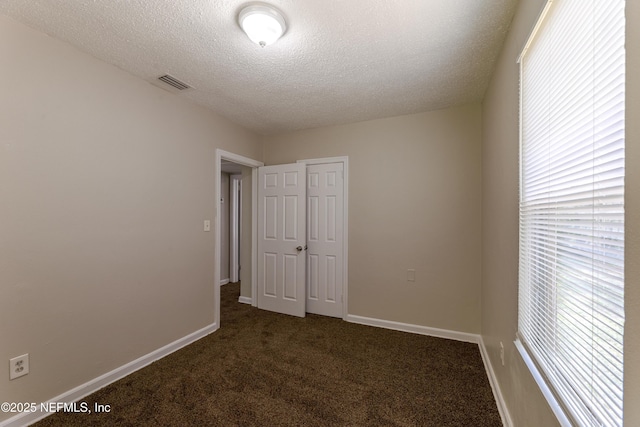 8344 Delaware Ave, Jacksonville, FL 32208 - unfurnished bedroom featuring dark colored carpet, visible vents, a closet, baseboards, and a textured ceiling