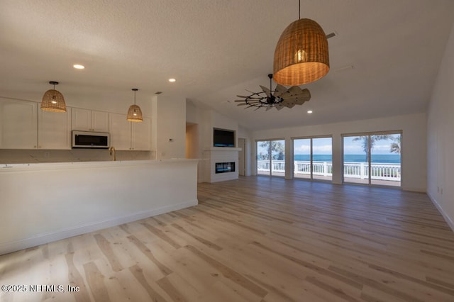 2818 Coastal Hwy, Saint Augustine, FL 32084 - unfurnished living room featuring a glass covered fireplace, light wood-style floors, baseboards, recessed lighting, and vaulted ceiling