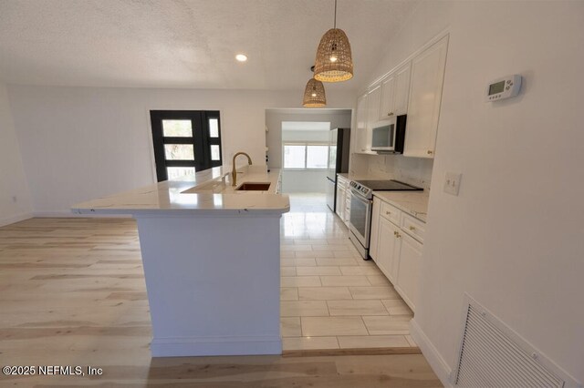2818 Coastal Hwy, Saint Augustine, FL 32084 - kitchen featuring decorative backsplash, a textured ceiling, a sink, white cabinets, and stainless steel appliances