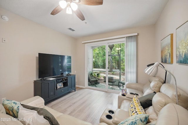 living area with baseboards, a ceiling fan, light wood finished floors, and visible vents
