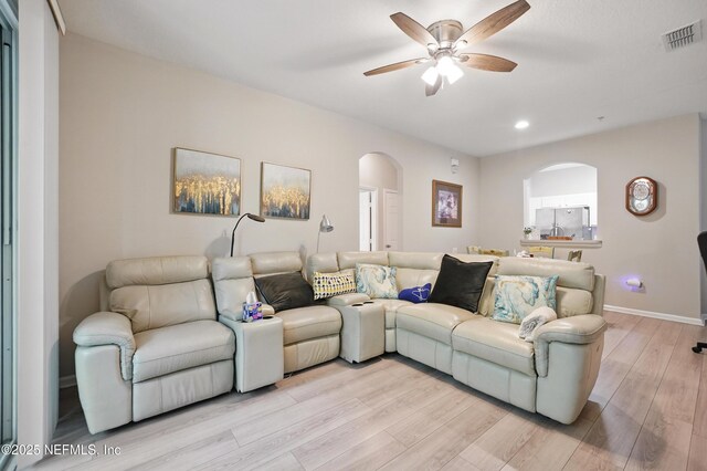 living room featuring arched walkways, a ceiling fan, recessed lighting, light wood-type flooring, and visible vents