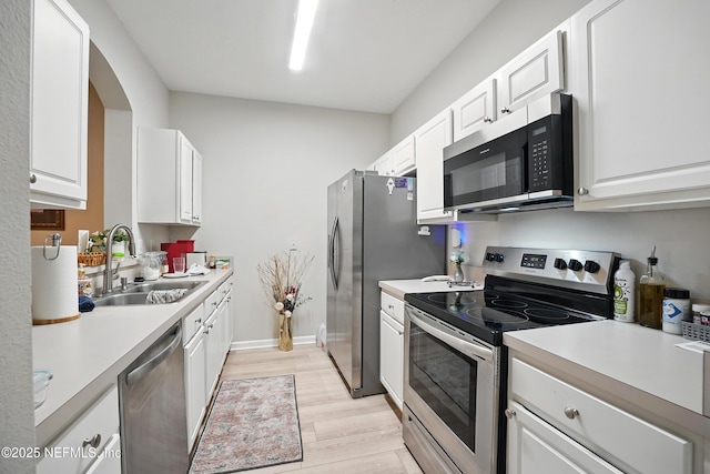 kitchen featuring a sink, appliances with stainless steel finishes, white cabinetry, and light countertops