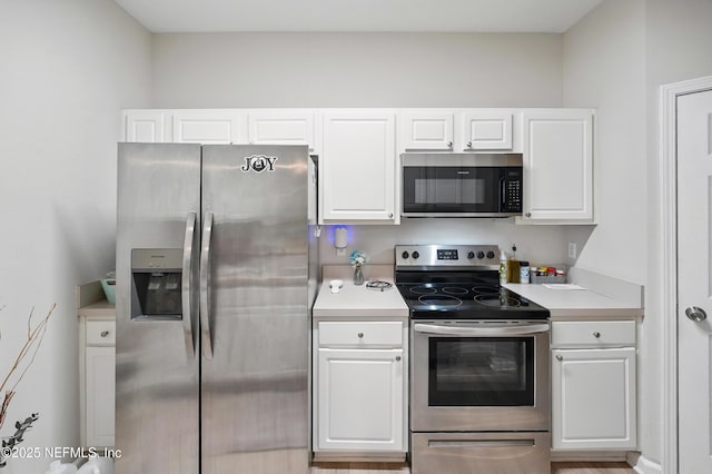 kitchen with light countertops, appliances with stainless steel finishes, and white cabinetry