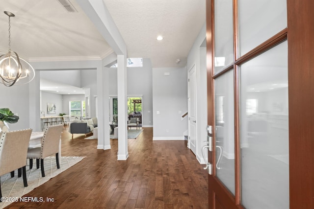 entryway with baseboards, dark wood-style flooring, ornamental molding, visible vents, and a chandelier