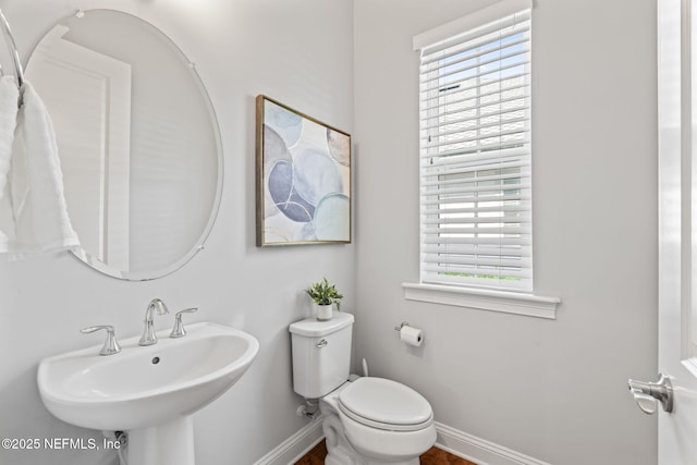 bathroom with a sink, toilet, and baseboards
