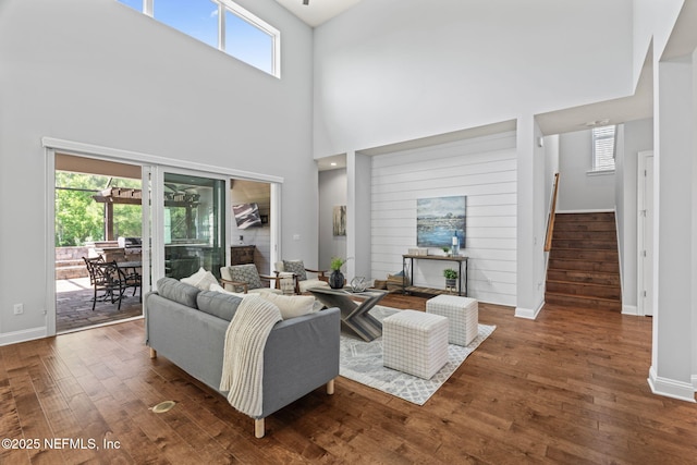 living room featuring baseboards, stairs, a towering ceiling, and wood finished floors