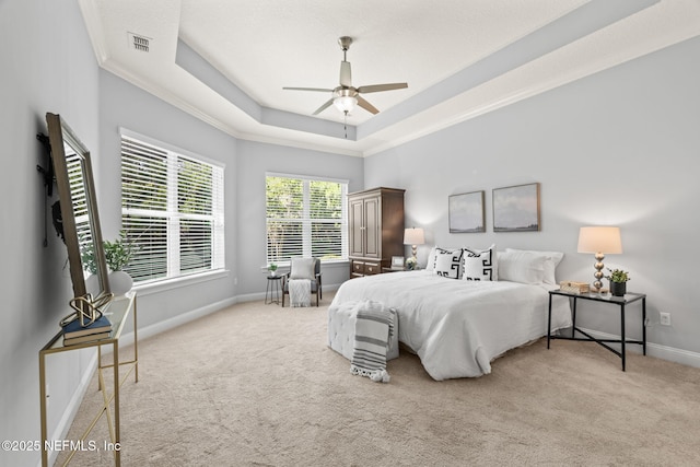 carpeted bedroom featuring ornamental molding, visible vents, ceiling fan, a tray ceiling, and baseboards
