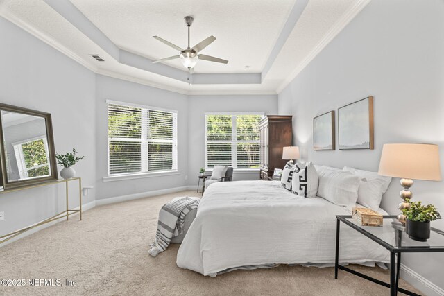 bedroom featuring ornamental molding, visible vents, carpet flooring, a tray ceiling, and baseboards