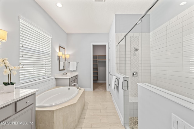 full bathroom featuring a stall shower, recessed lighting, a garden tub, vanity, and a spacious closet