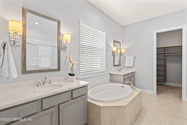 bathroom with a sink, tiled shower, two vanities, and a bath