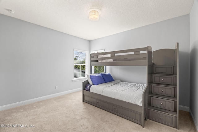 bedroom with light colored carpet, a textured ceiling, and baseboards