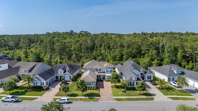 drone / aerial view featuring a wooded view and a residential view