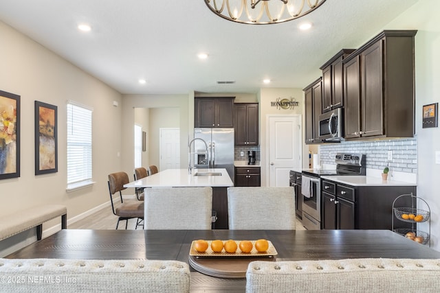 2793 Pointed Leaf Rd, Green Cove Springs, FL 32043 - kitchen featuring backsplash, dark brown cabinetry, an island with sink, and stainless steel appliances